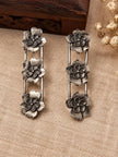 Two oxidised silver flower drop earrings laid flat on burlap beside a carved wooden box
