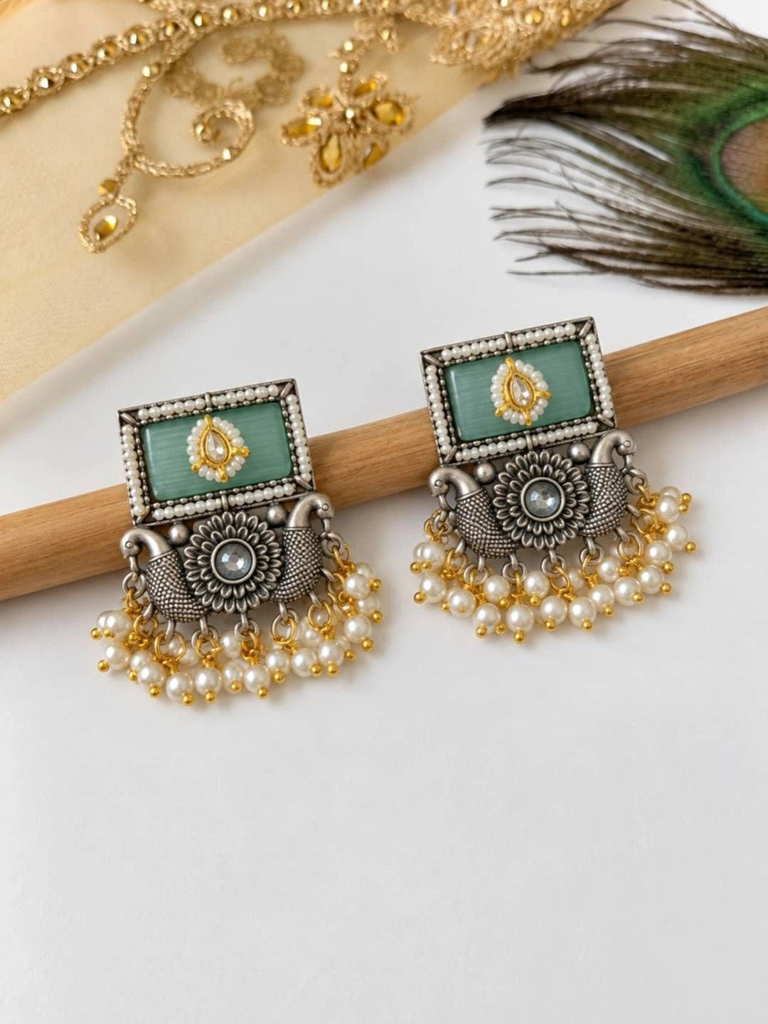 Pair of oxidised silver kundan rectangular drop earrings displayed on wooden rod with pearl fringe visible