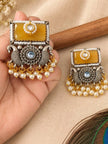 Pair of oxidised silver chandbali earrings held in hand showing peacock motif and pearl bead fringe
