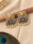 Both oxidised silver chandbali earrings resting on wooden stick showing yellow stone and pearl drops