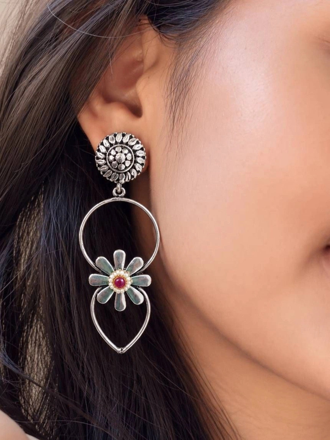 Oxidised silver daisy hoop drop earring worn on a model's ear showing scale and drape