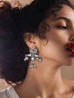 Oxidised silver peacock drop earring worn on a model's ear with red flower