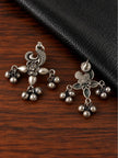 Front and back view of oxidised silver peacock earrings on a wooden surface