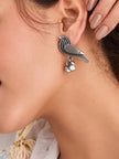 Close-up of oxidised silver bird stud earring with ghungroo cluster worn on a woman's ear