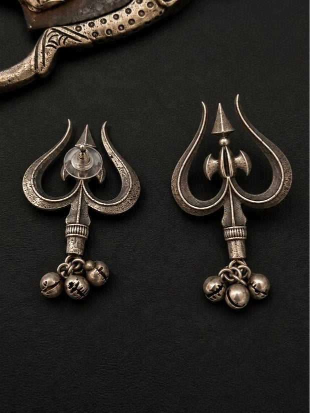 Front and back view of oxidised silver trishul stud earrings with ghungroo bell drops on dark background