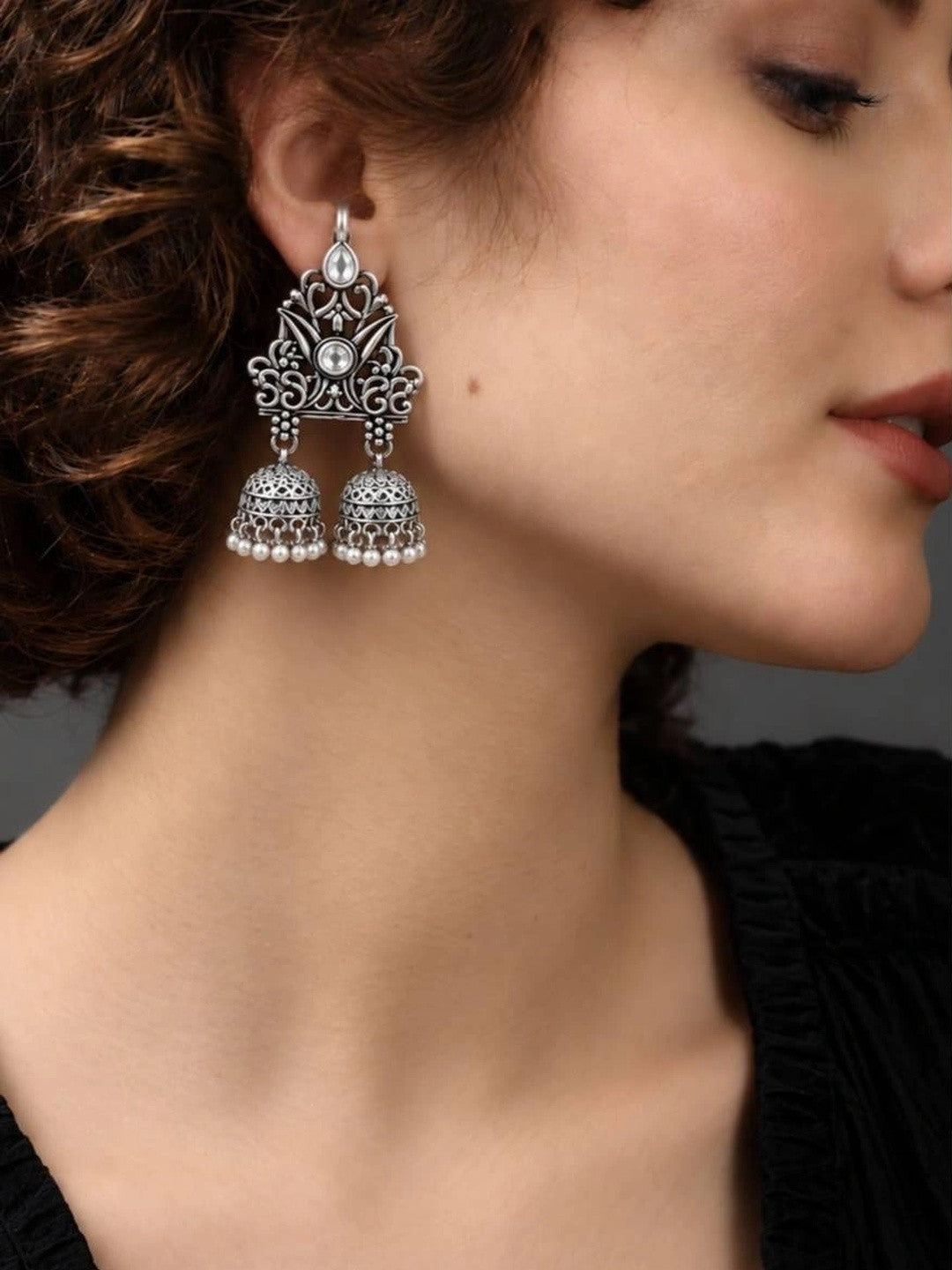 Model wearing oxidised silver double jhumka earring with filigree lotus top panel and twin bell drops