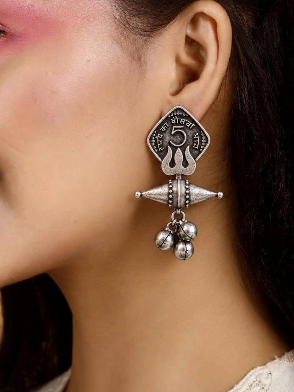 Close-up of oxidised silver coin drop earring worn on a woman's ear showing full length and scale