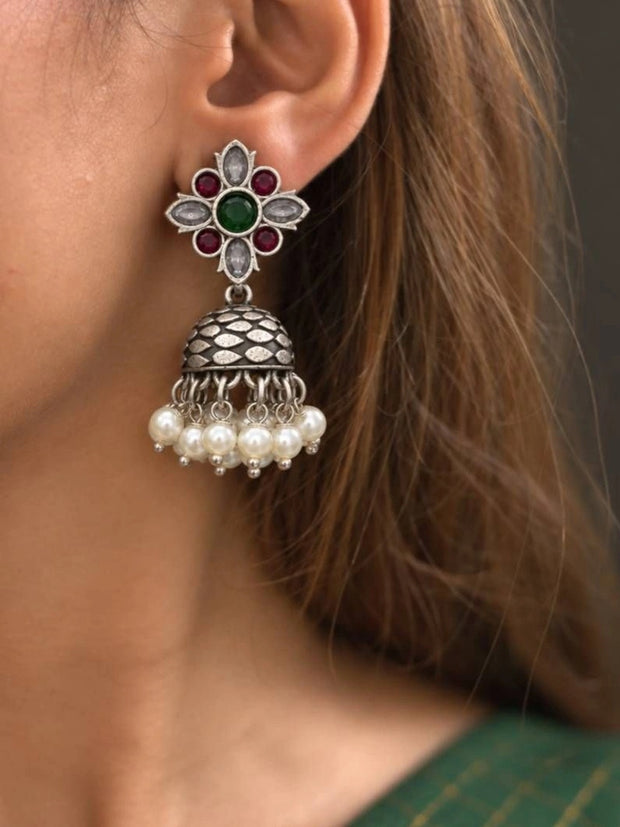 Oxidised silver floral kundan jhumka with pearl drops worn on a woman's ear