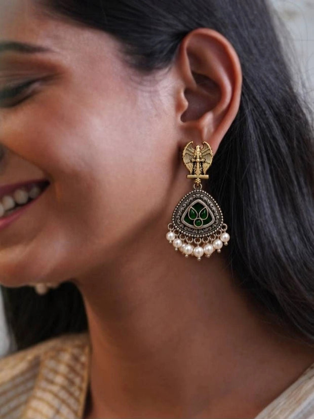Woman wearing oxidised gold Garuda chandbali earring with green resin stones and white pearl drops