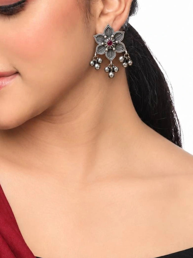 Oxidised silver floral stud earring with red stone and ghungroo bells worn on model's ear