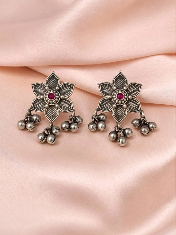 Pair of oxidised silver floral earrings with engraved petals and dangling bell drops on pink satin