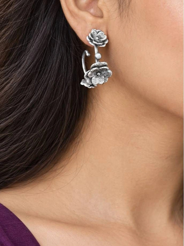 Model wearing one oxidised silver floral ear cuff earring on her left ear with a purple top