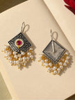 Front and back view of oxidised silver pearl drop earrings laid flat on cream surface