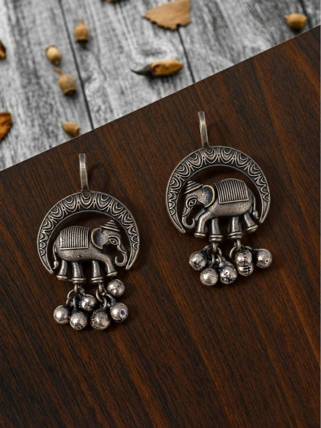 Pair of oxidised silver crescent elephant drop earrings showing engraved scrollwork detail