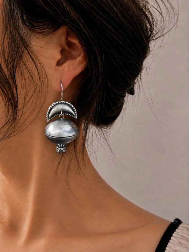 Oxidised silver dome jhumka earring worn on model showing crescent arch top and bead drop