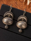 Pair of oxidised silver dome jhumka earrings laid flat on black jewellery display tray