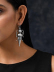 Woman wearing an oxidised silver goddess figure drop earring on shepherd hook wire against a dark background
