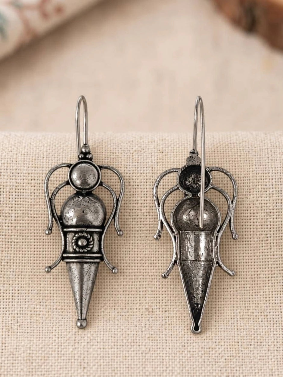 Front and back view of oxidised silver goddess drop earrings showing scrollwork detail on linen surface