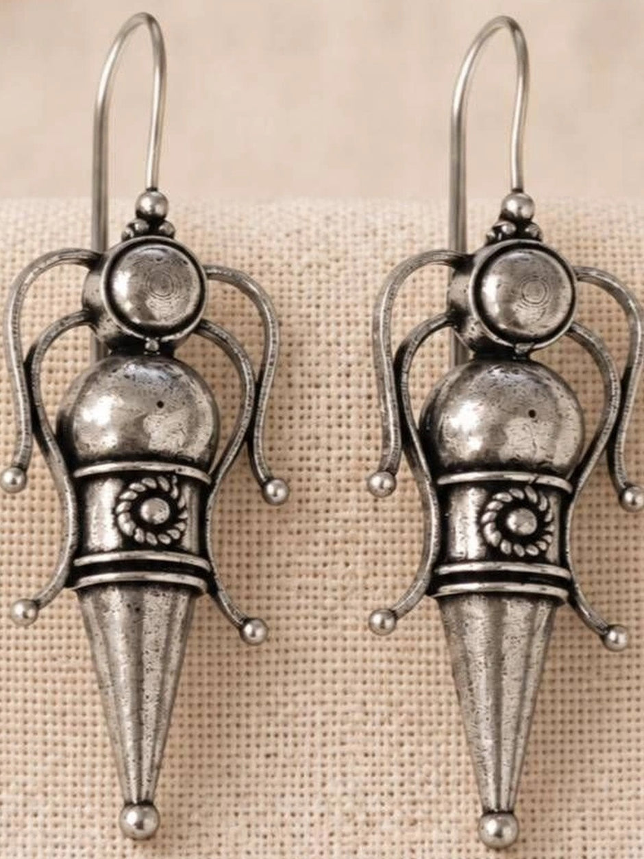 Pair of oxidised silver goddess figure earrings with domed head, ball terminals and conical base on linen