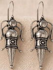 Pair of oxidised silver goddess figure earrings with domed head, ball terminals and conical base on linen