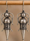 Close-up of two oxidised silver goddess drop earrings hanging on a wooden rod showing engraved medallion waist detail