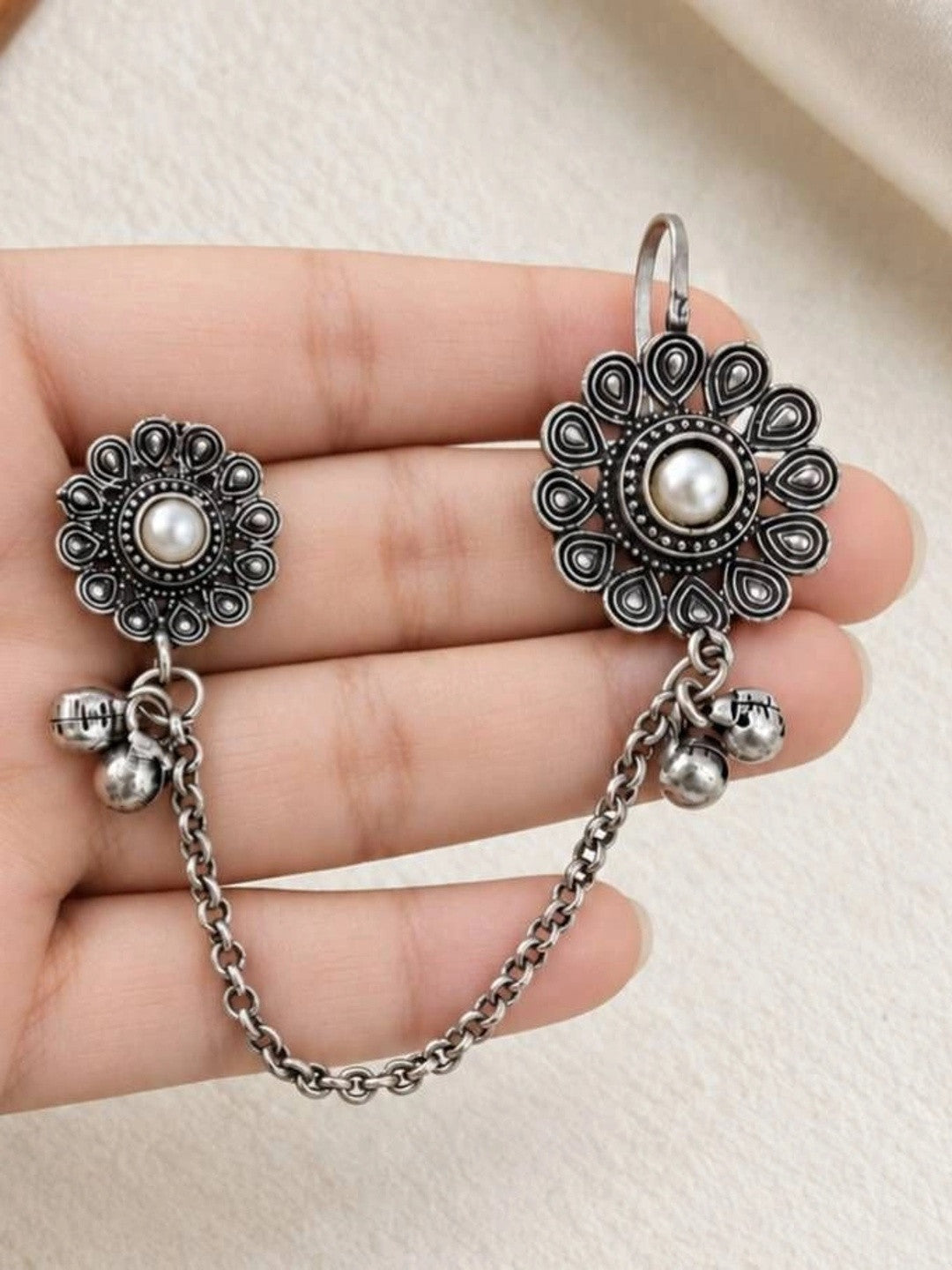 Oxidised silver floral ear cuff and stud earring with pearl centre held in an open palm showing chain and ghungroo detail
