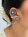 Oxidised silver floral ear cuff worn on model's ear with stud on lobe connected by silver chain, styled with pearl hair bun