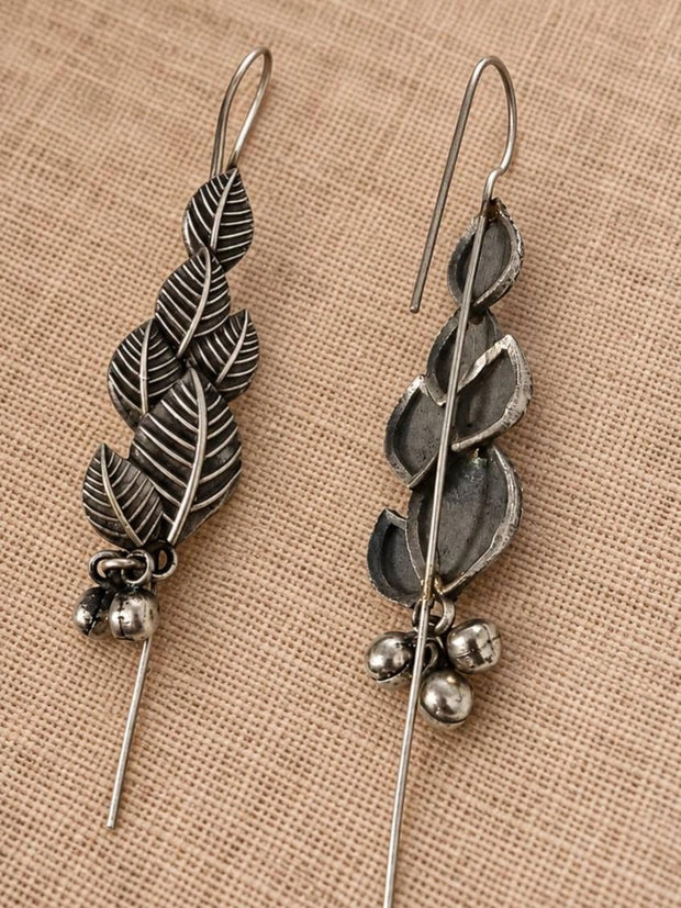 Front and back view of oxidised silver leaf earrings showing threader hook and ghungroo bells on linen