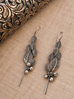 Pair of oxidised silver leaf earrings with ghungroo bells laid flat on linen beside a carved box