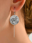 Close-up of oxidised silver karma coin drop earring worn on a womans ear showing scale and shepherd-hook closure