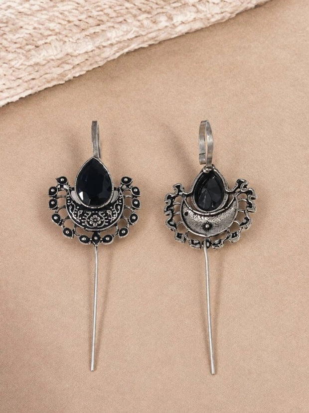 Front and back view of oxidised silver ear cuff earrings with black teardrop stone on a beige surface