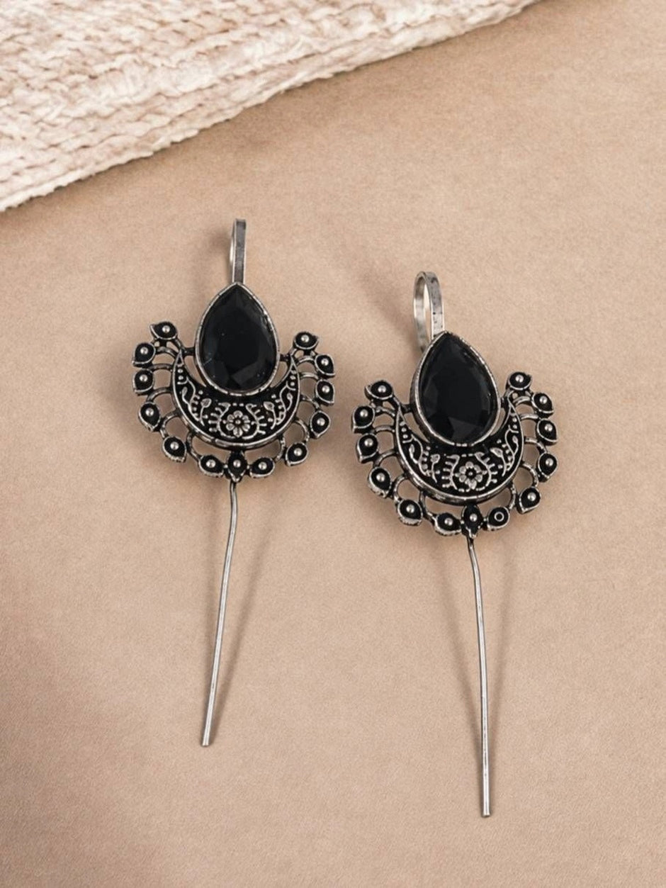 Pair of oxidised silver crescent ear cuff earrings with black stone and long threader pin on beige background
