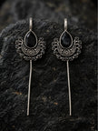 Pair of oxidised silver ear cuff earrings with black stone displayed on dark textured rock surface