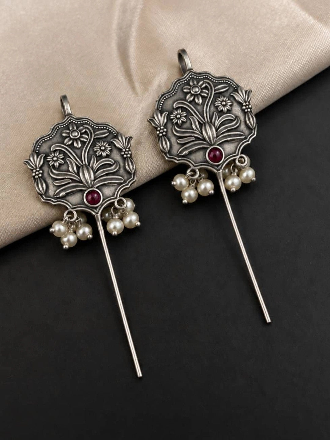 Pair of oxidised silver ear cuff earrings with botanical motif and ivory pearl clusters on dark surface