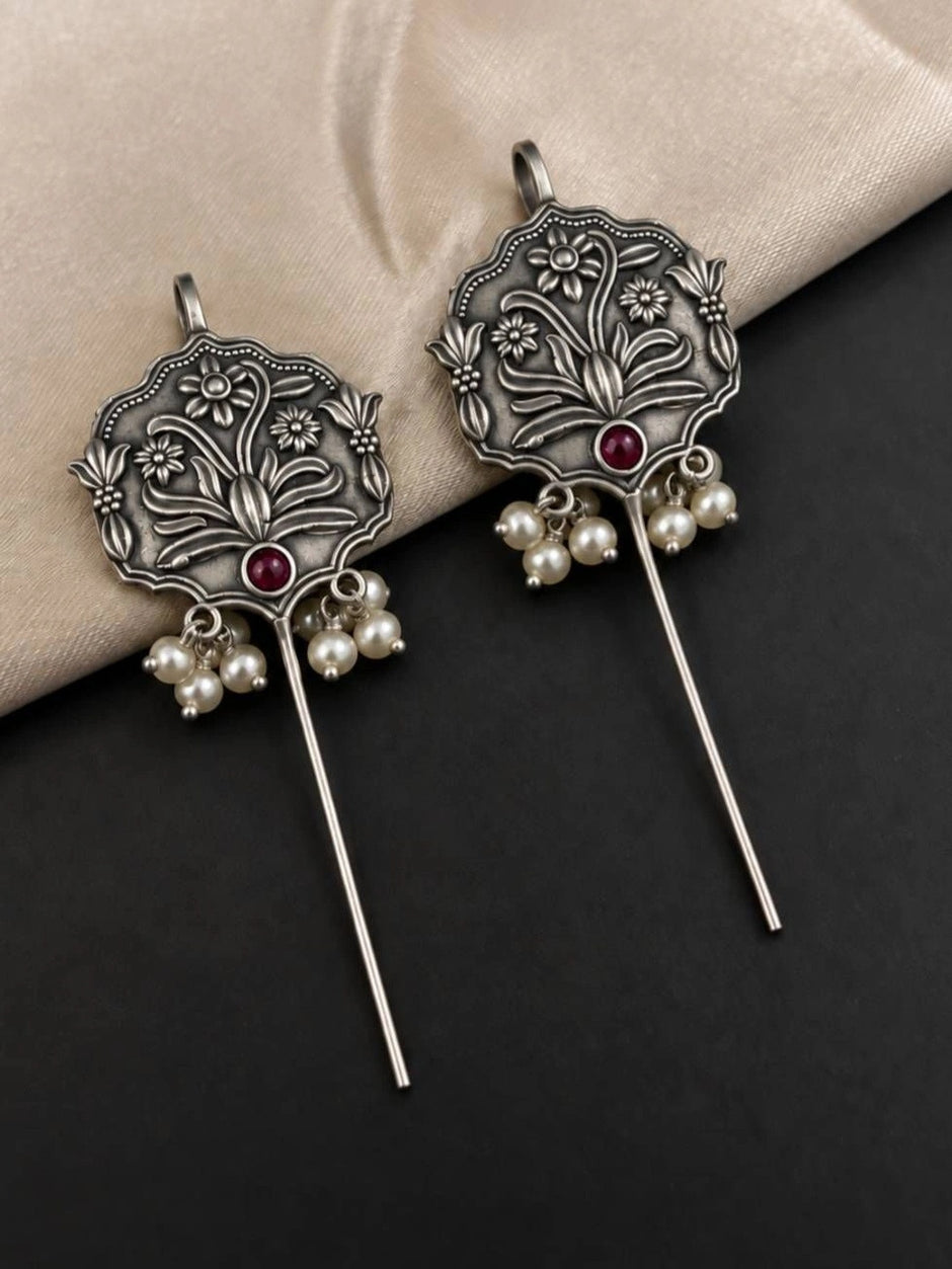 Pair of oxidised silver ear cuff earrings with botanical motif and ivory pearl clusters on dark surface