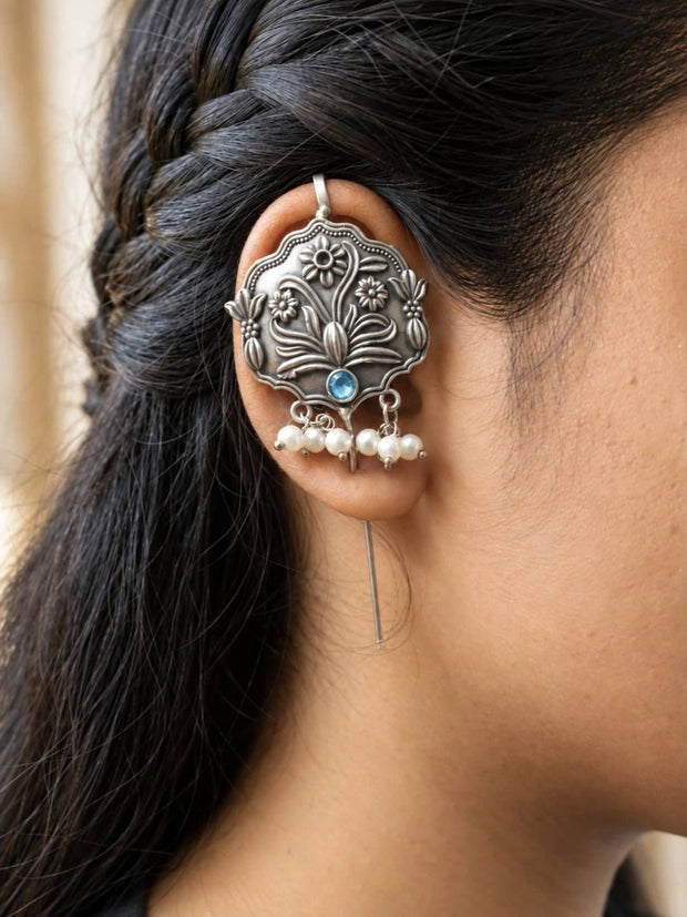 Oxidised silver floral ear cuff worn on a woman's ear showing carved medallion and pearl drops