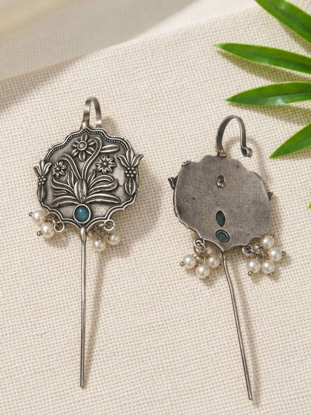 Front and back view of oxidised silver floral ear cuff earrings laid flat on white fabric