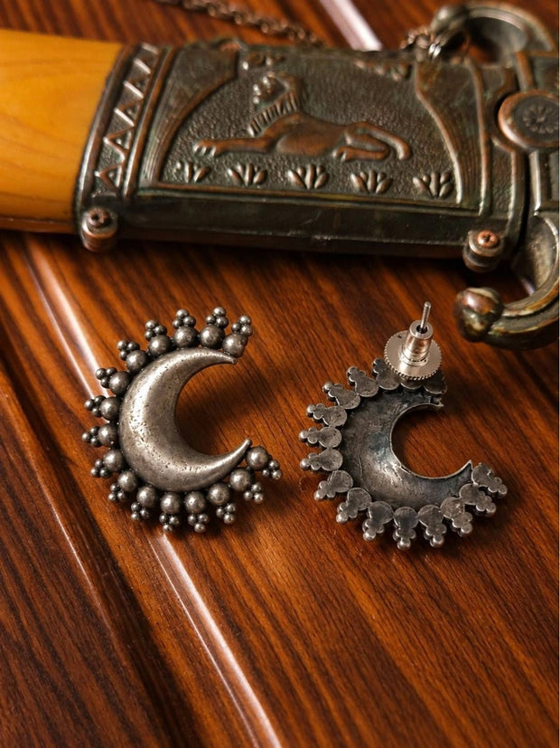 Oxidised silver crescent moon stud earring front and back view on a wooden surface beside a decorative silver box