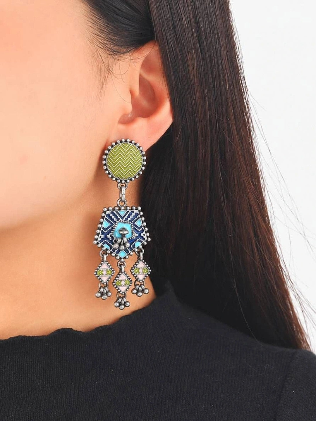 Model wearing one oxidised silver enamel geometric drop earring against a plain white background with black top