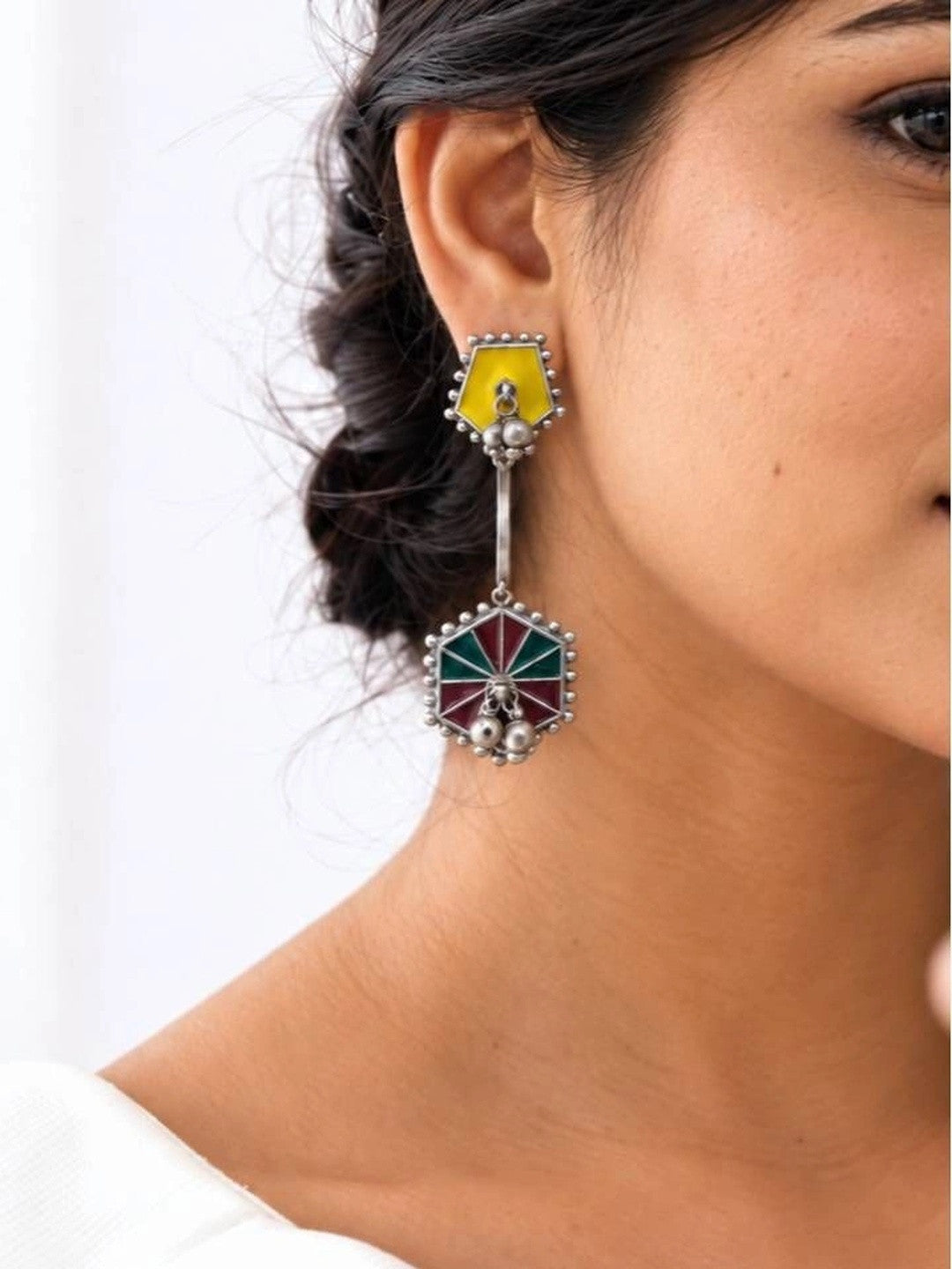 Woman wearing oxidised silver hexagonal drop earring with yellow stud and teal maroon enamel pendant at side profile