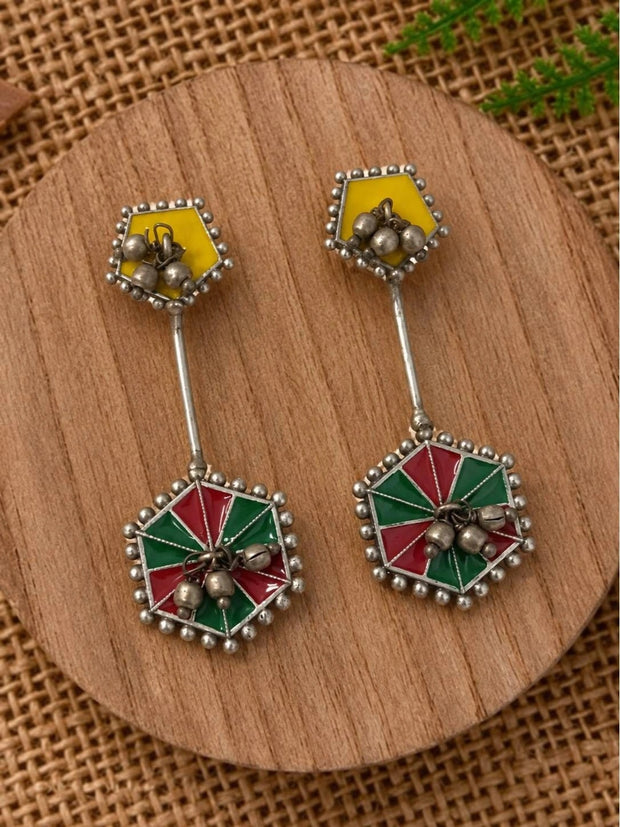 Pair of oxidised geometric enamel drop earrings with ghungroo bells displayed on a round wooden surface