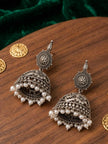 Pair of oxidised silver filigree jhumka earrings with pearl fringe laid on wooden surface