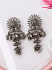 Pair of oxidised silver cascading jhumka earrings with sun-burst tops and tiered umbrella drops laid flat on white surface