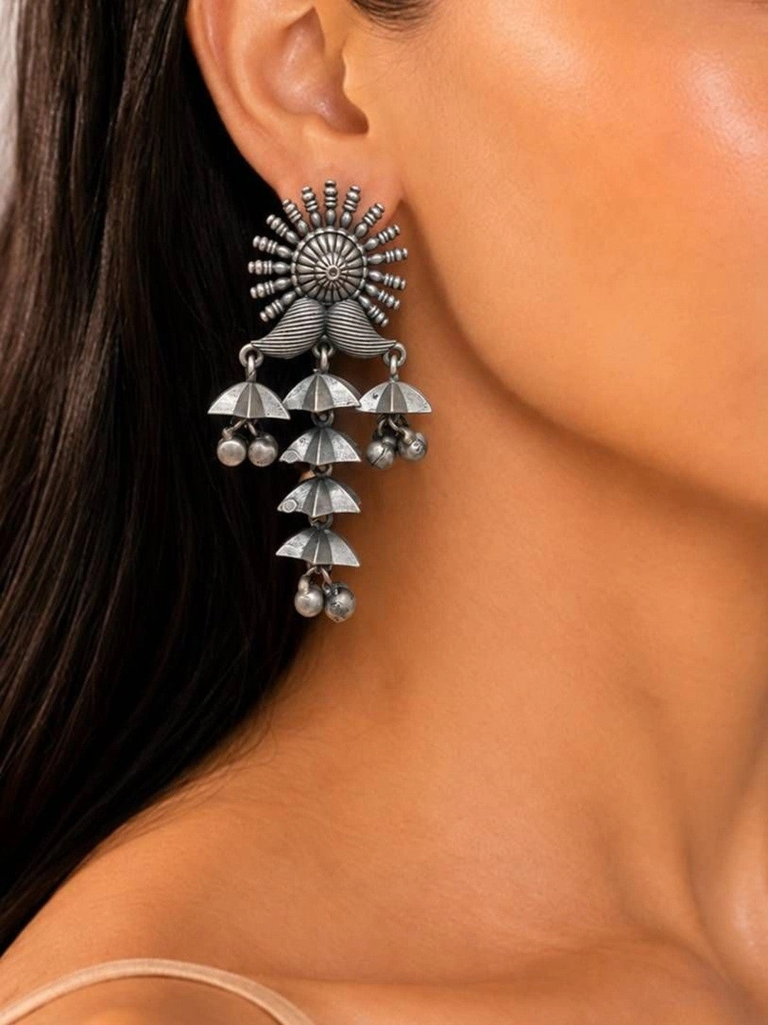 Oxidised silver cascading jhumka earring worn on a model's ear showing full length and sun-burst stud top