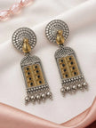 Pair of oxidised silver jhumka earrings with gold-tone haveli door pendant and black stones laid flat on white fabric