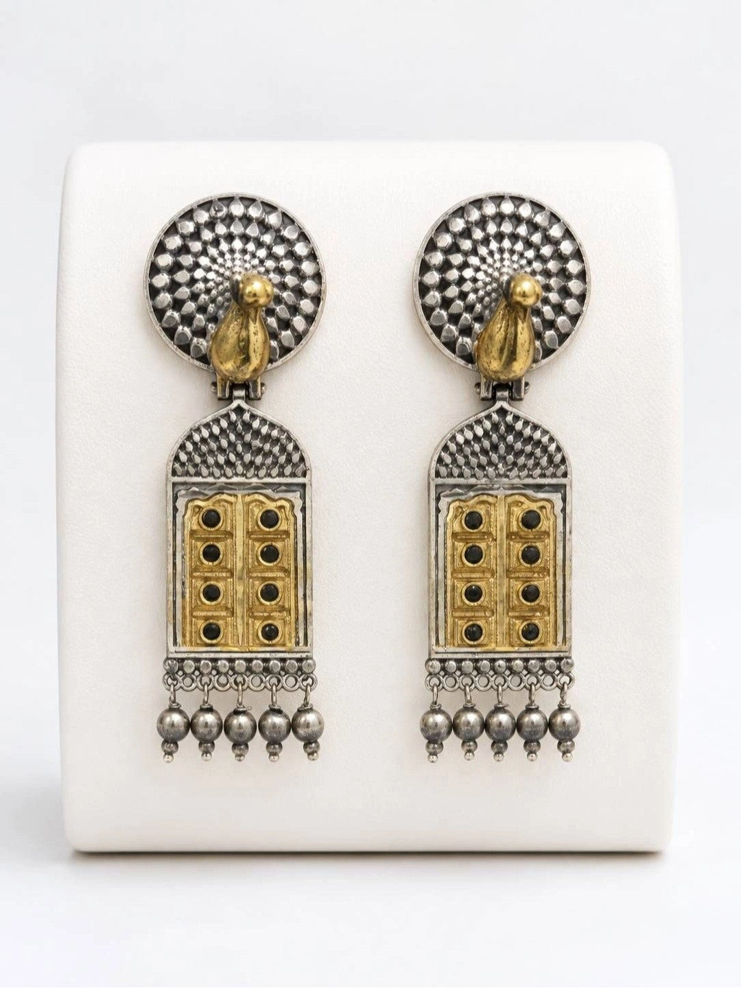 Front view of both earrings displayed upright on white earring stand showing textured circular top and arch pendant