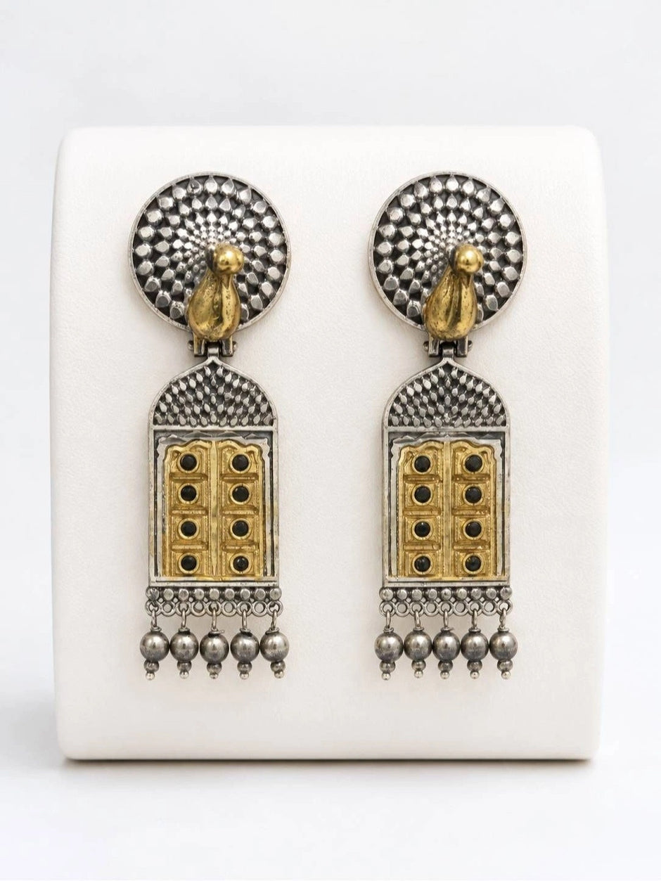 Front view of both earrings displayed upright on white earring stand showing textured circular top and arch pendant