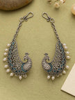 Pair of oxidised silver peacock ear cuff earrings with teal enamel and white pearl drops on sage green background