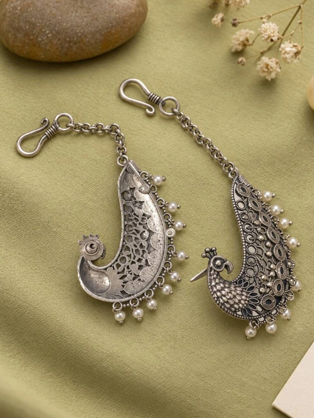 Back view of oxidised silver peacock ear cuffs showing plain reverse side and hook-and-chain mechanism