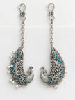 Pair of oxidised silver peacock ear cuffs with teal enamel laid flat on white background